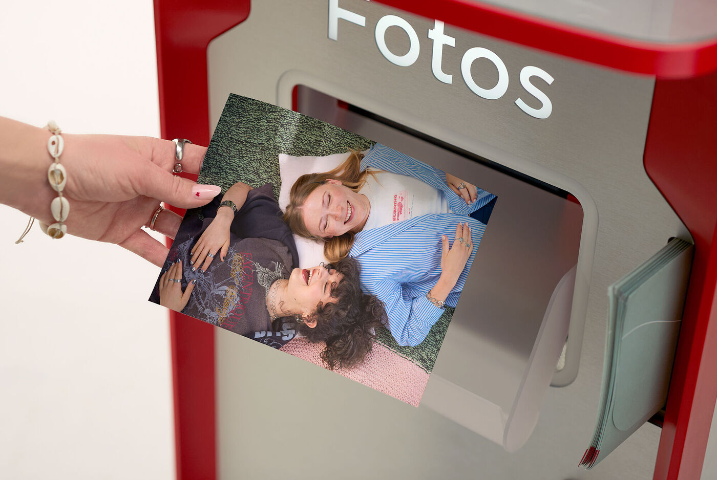 Eine Person nimmt ein Foto aus der CEWE Fotostation.