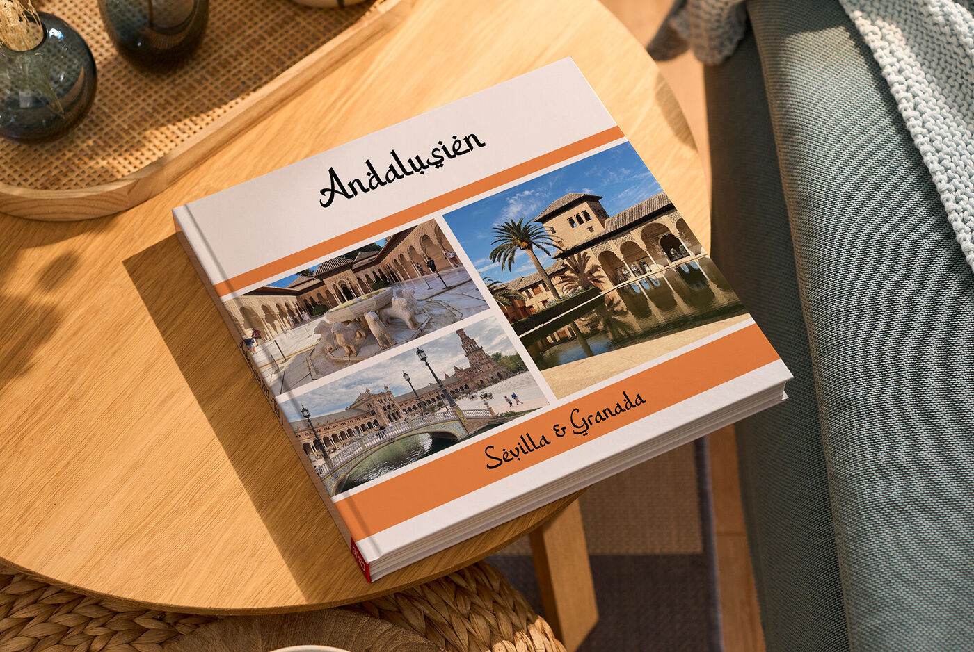Auf einem kleinen Holztisch liegt ein CEWE FOTOBUCH. Darauf sind drei Fotos und der Schriftzug "Andalusien" zu sehen.